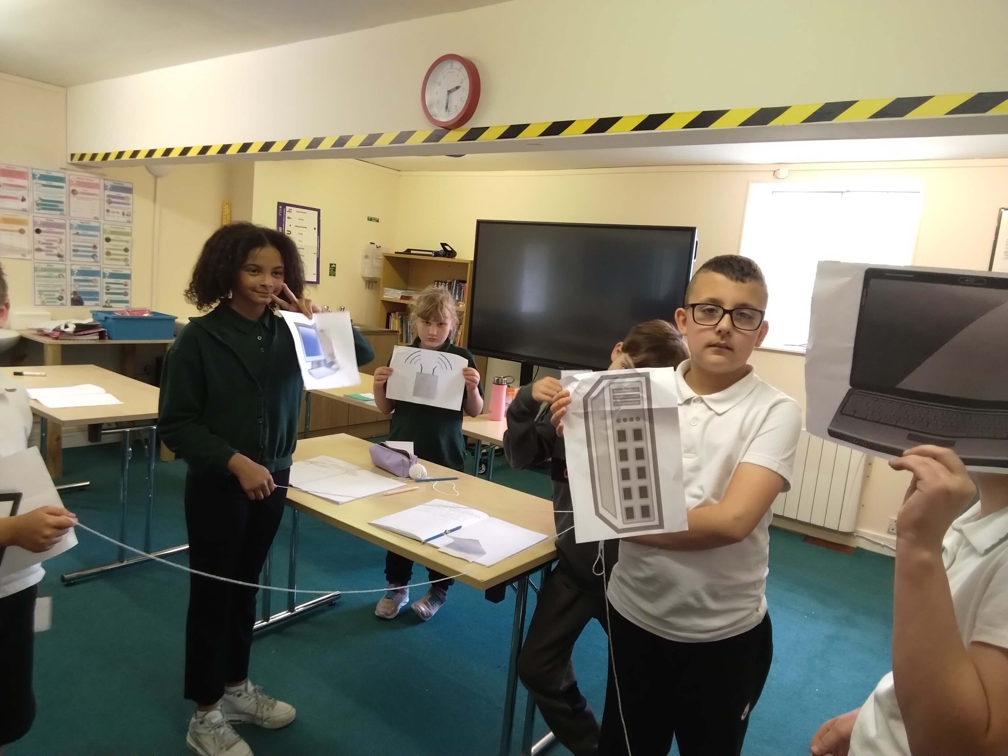 Students showcasing printed pictures of devices